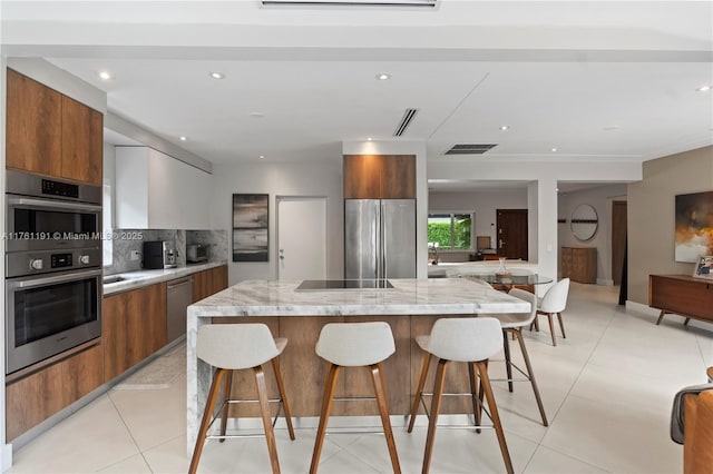 kitchen with a kitchen island, a kitchen bar, appliances with stainless steel finishes, modern cabinets, and brown cabinets