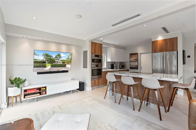 kitchen featuring visible vents, a breakfast bar, modern cabinets, brown cabinets, and appliances with stainless steel finishes