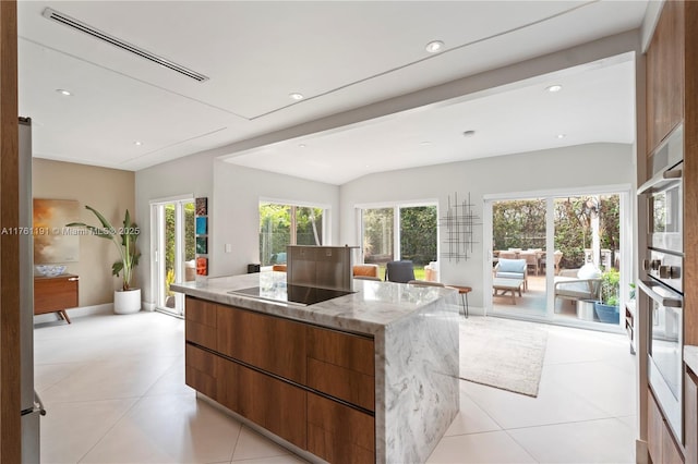 kitchen with light tile patterned flooring, black electric cooktop, modern cabinets, light stone countertops, and a center island