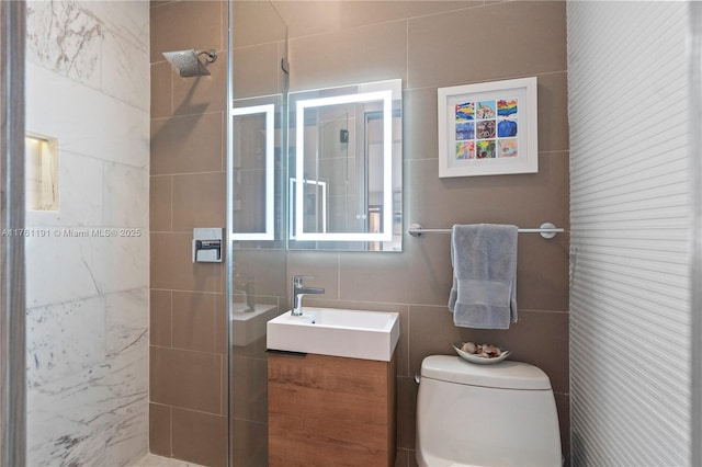 bathroom with vanity, toilet, tile walls, and a shower stall