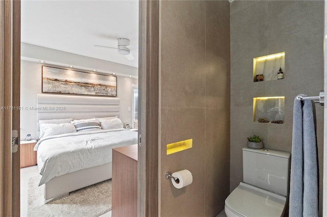 ensuite bathroom featuring tile walls, toilet, ceiling fan, and ensuite bathroom