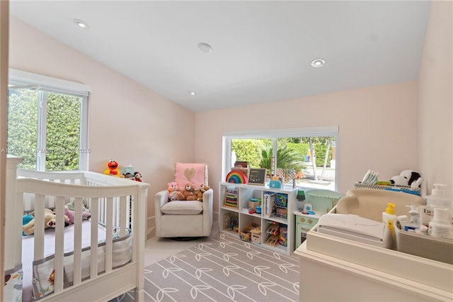 carpeted bedroom with a nursery area, vaulted ceiling, and recessed lighting