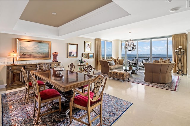 dining space featuring an inviting chandelier, ornamental molding, a tray ceiling, and expansive windows