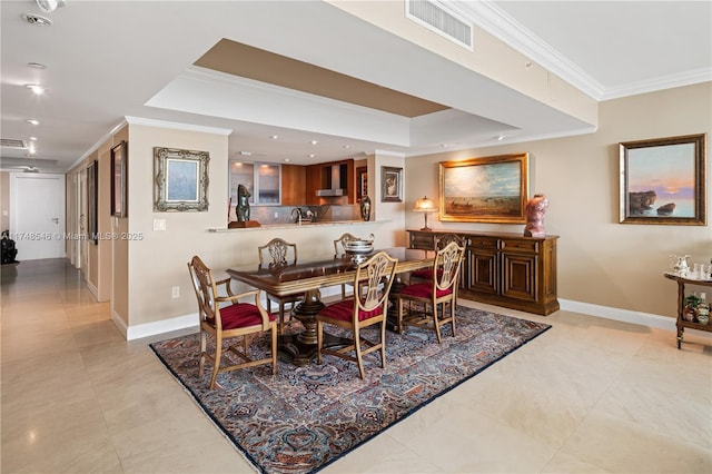 dining room featuring a tray ceiling, baseboards, visible vents, and ornamental molding