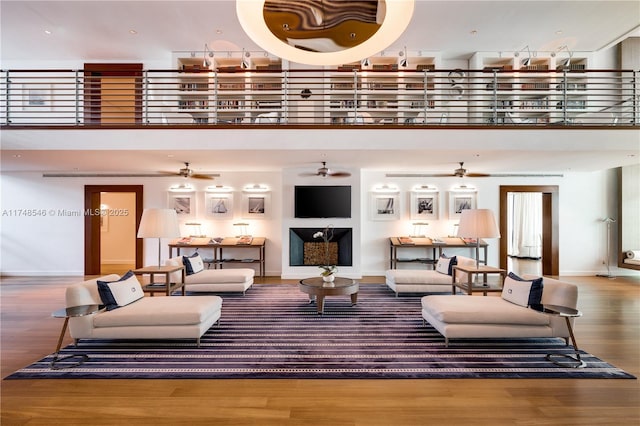 living area featuring baseboards, a high ceiling, a ceiling fan, and wood finished floors