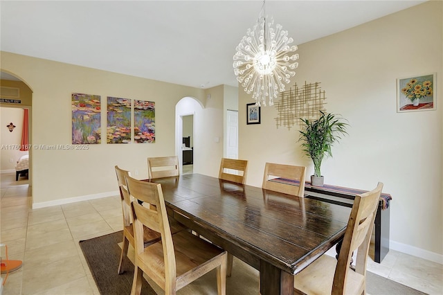 dining space featuring arched walkways, light tile patterned floors, a chandelier, and baseboards