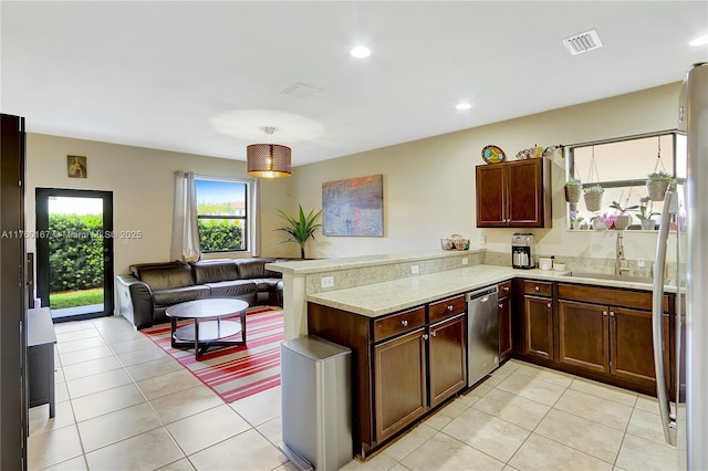 kitchen with visible vents, a peninsula, a sink, stainless steel appliances, and light countertops