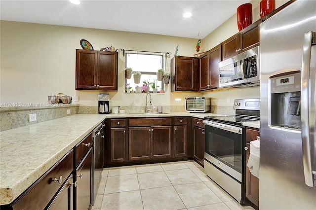 kitchen with a sink, stainless steel appliances, light tile patterned flooring, light countertops, and dark brown cabinets