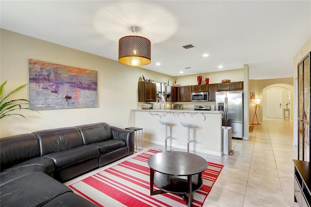 living area featuring visible vents, baseboards, light tile patterned floors, recessed lighting, and arched walkways