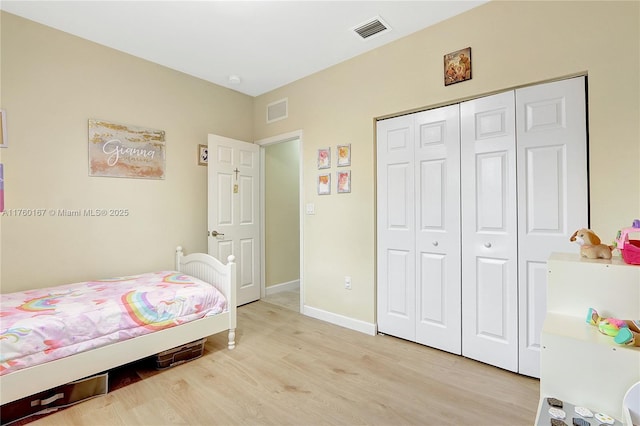 bedroom with a closet, baseboards, visible vents, and light wood finished floors