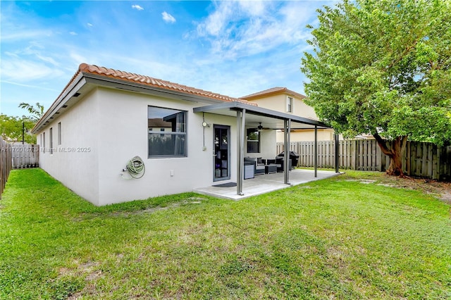 back of house featuring a ceiling fan, a fenced backyard, a lawn, and stucco siding