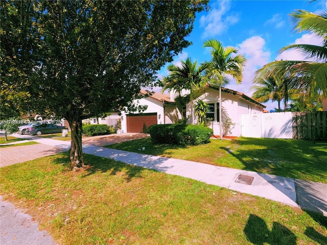 view of front of property featuring a front yard, fence, driveway, stucco siding, and a garage