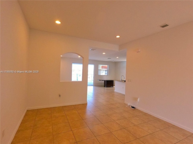 spare room with arched walkways, visible vents, recessed lighting, and light tile patterned floors
