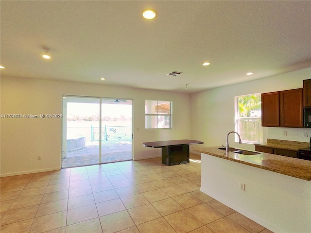 kitchen featuring a sink, black microwave, recessed lighting, and light tile patterned floors