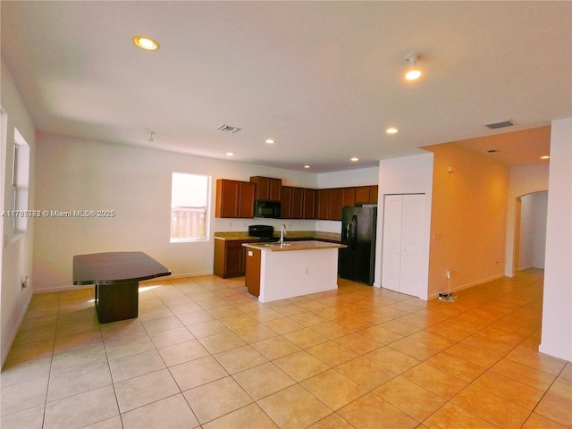 kitchen with visible vents, light tile patterned floors, recessed lighting, black appliances, and a kitchen island with sink