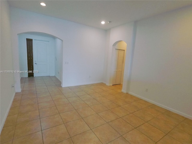 unfurnished room with recessed lighting, baseboards, arched walkways, and light tile patterned flooring