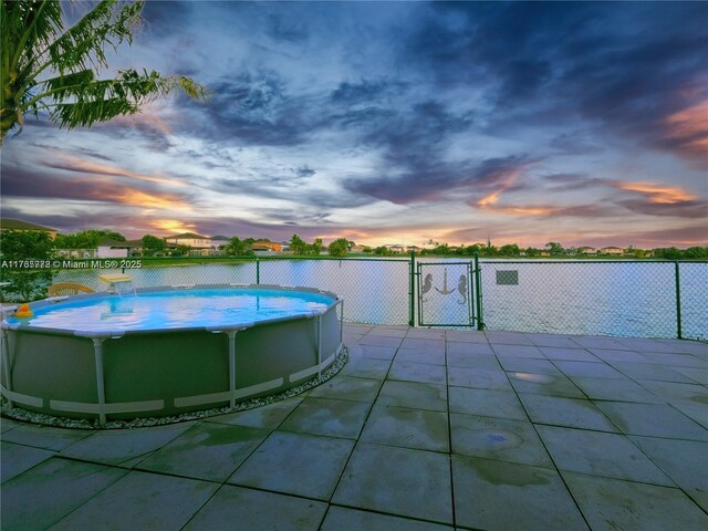 pool at dusk with a fenced in pool, fence, a patio, and a gate