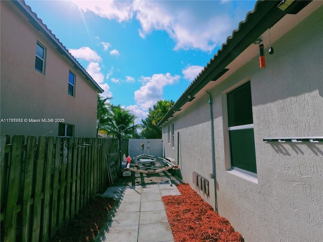 view of side of property with stucco siding, a patio, and fence