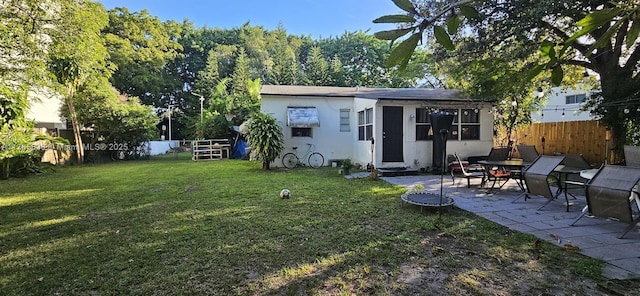 rear view of property featuring stucco siding, a lawn, a fenced backyard, and a patio area
