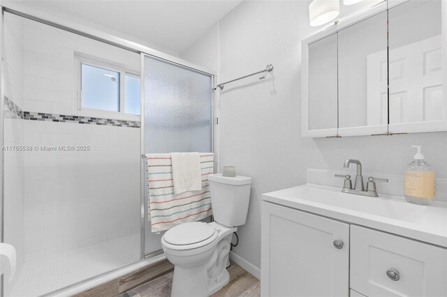 bathroom featuring toilet, vanity, wood finished floors, and a shower stall