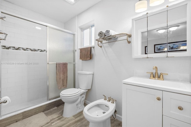 bathroom with vanity, toilet, a stall shower, a bidet, and wood finished floors