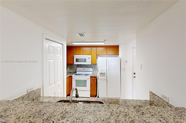 1650 Coral Way Unit Ph-9, Miami, FL 33145 - kitchen featuring white appliances, a sink, light stone counters, backsplash, and brown cabinetry
