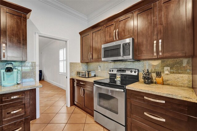 kitchen featuring a sink, light tile patterned flooring, appliances with stainless steel finishes, light stone counters, and ornamental molding