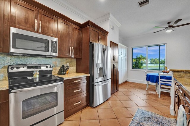 kitchen with dark brown cabinets, ornamental molding, light tile patterned floors, decorative backsplash, and appliances with stainless steel finishes