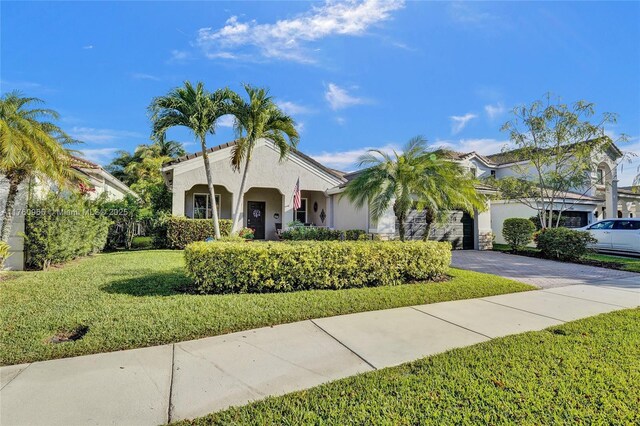 mediterranean / spanish-style house with an attached garage, a front lawn, stucco siding, and decorative driveway
