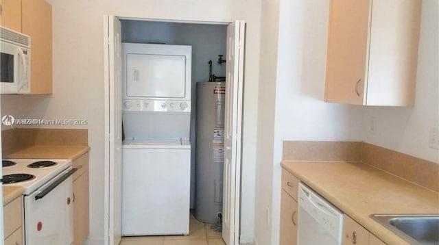 kitchen featuring electric water heater, light countertops, light tile patterned flooring, white appliances, and stacked washer / drying machine