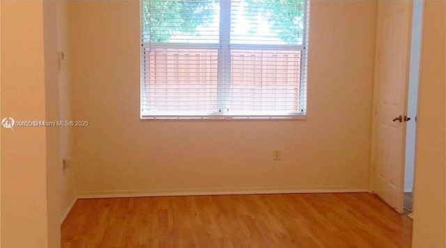 empty room featuring a wealth of natural light, baseboards, and wood finished floors