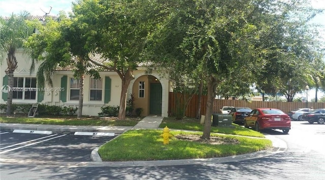 view of front of home with stucco siding, fence, and uncovered parking