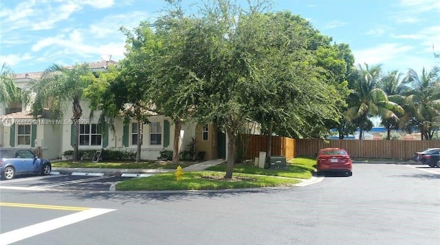view of front of home featuring stucco siding, uncovered parking, and fence