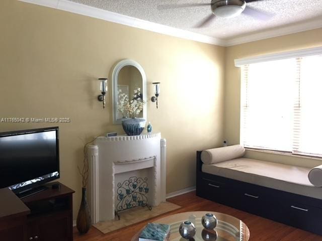 interior space with wood finished floors, a textured ceiling, ceiling fan, and crown molding