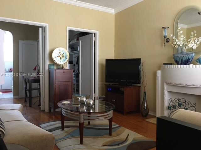 living area featuring baseboards, crown molding, and wood finished floors
