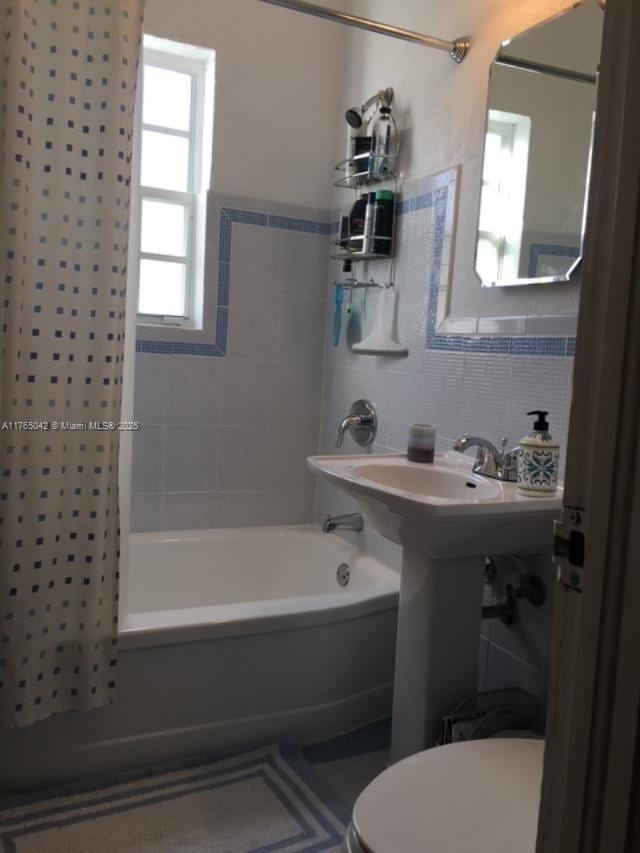 full bath with toilet, washtub / shower combination, and tile walls