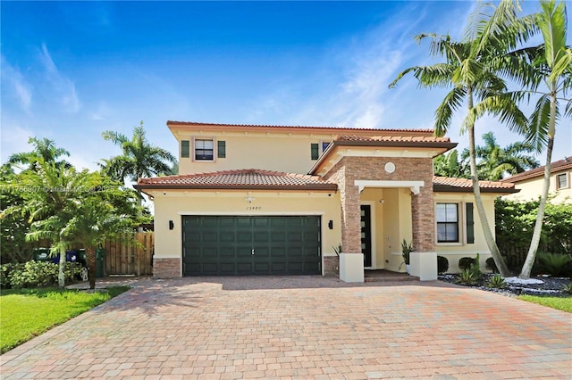mediterranean / spanish-style house with stucco siding, a tile roof, decorative driveway, and a garage