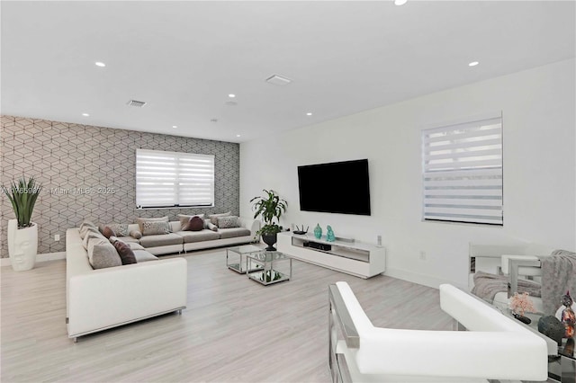 living area featuring recessed lighting, an accent wall, and wood finished floors
