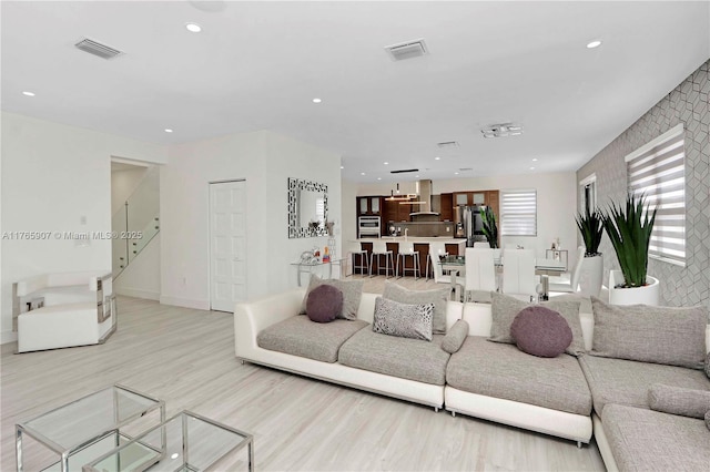living area with visible vents, recessed lighting, light wood-style flooring, and baseboards