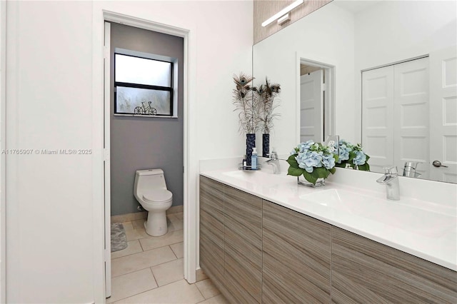 bathroom featuring tile patterned floors, double vanity, toilet, and a sink