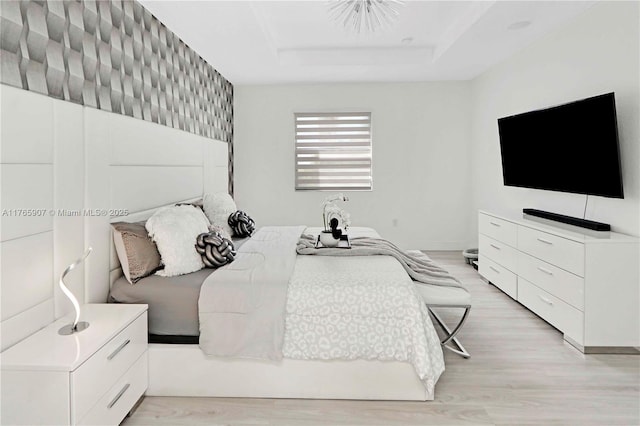 bedroom featuring a tray ceiling and light wood-type flooring