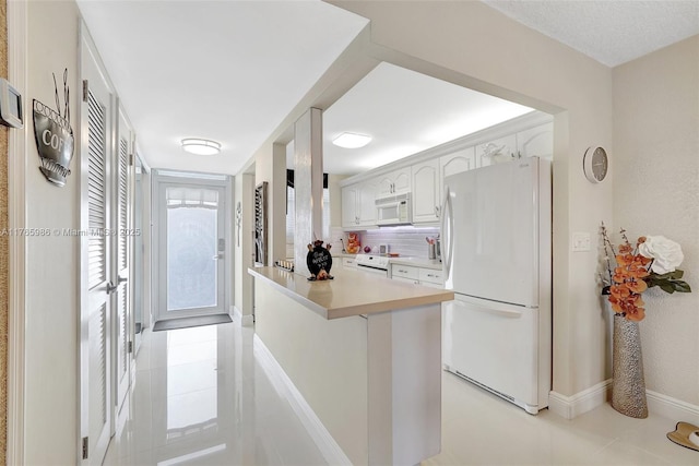 410 Golden Isles Dr Unit 603, Hallandale Beach, FL 33009 - kitchen featuring white appliances, light tile patterned floors, decorative backsplash, light countertops, and white cabinets