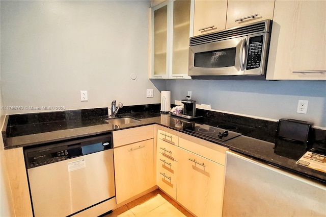 kitchen featuring dark stone counters, light tile patterned flooring, a sink, stainless steel appliances, and glass insert cabinets