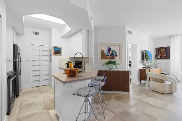 888 Brickell Key Dr Unit 1502, Miami, FL 33131 - kitchen featuring black electric range, a peninsula, a breakfast bar area, light countertops, and freestanding refrigerator