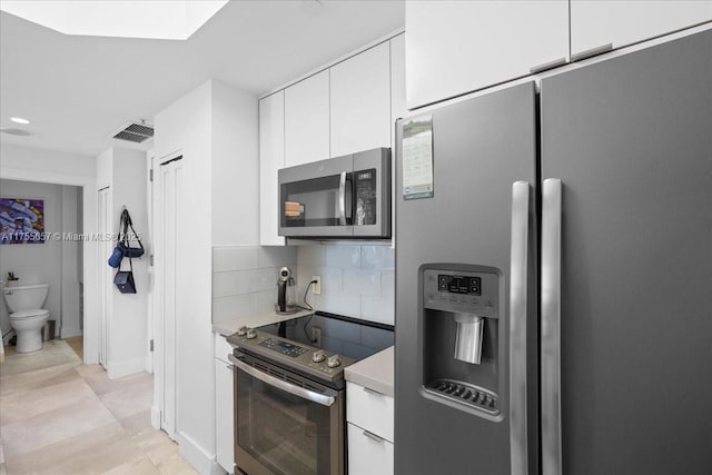 888 Brickell Key Dr Unit 1502, Miami, FL 33131 - kitchen featuring appliances with stainless steel finishes, light countertops, white cabinets, decorative backsplash, and light tile patterned flooring