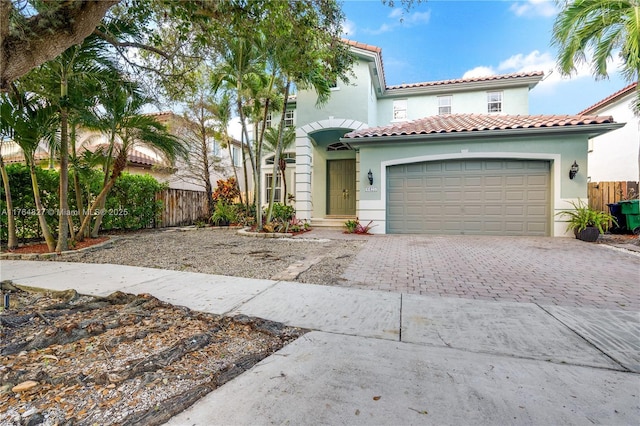 mediterranean / spanish-style home with driveway, stucco siding, and fence