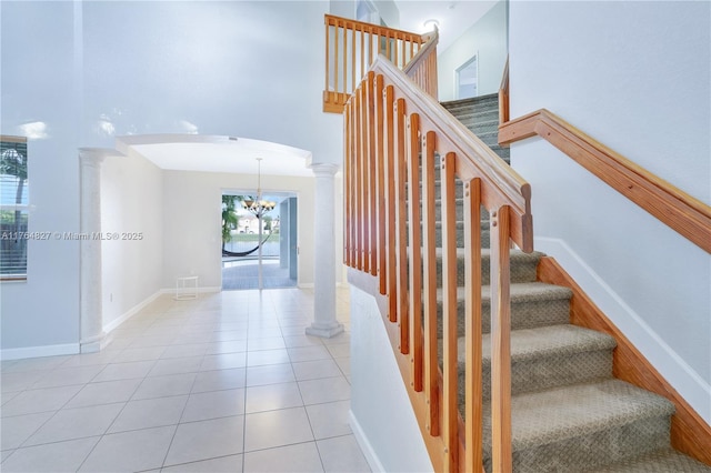 stairway featuring decorative columns, a notable chandelier, arched walkways, and tile patterned flooring