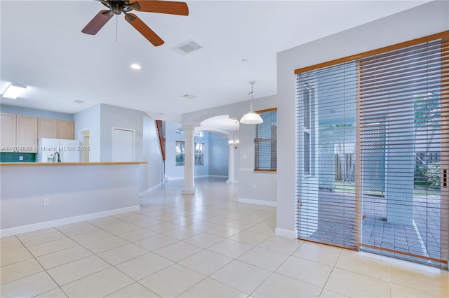 interior space with light tile patterned flooring, visible vents, ornate columns, a ceiling fan, and arched walkways
