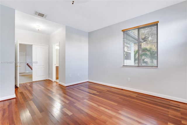 empty room with baseboards, visible vents, and wood finished floors