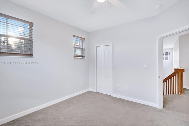 carpeted empty room with a ceiling fan and baseboards